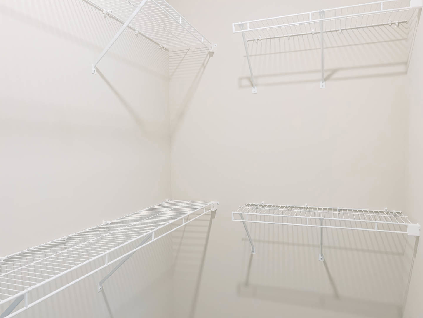 Pair of white floating shelves mounted on a light-colored wall in a modern room, casting soft shadows and displaying minimal decor