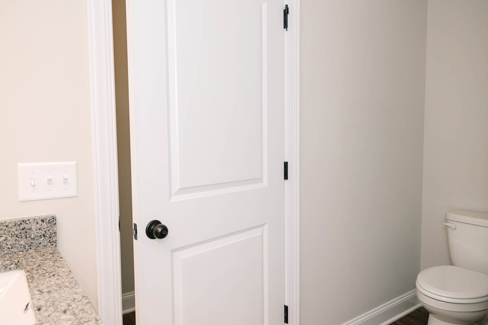 White paneled door with matte black round knob set against a smooth white wall