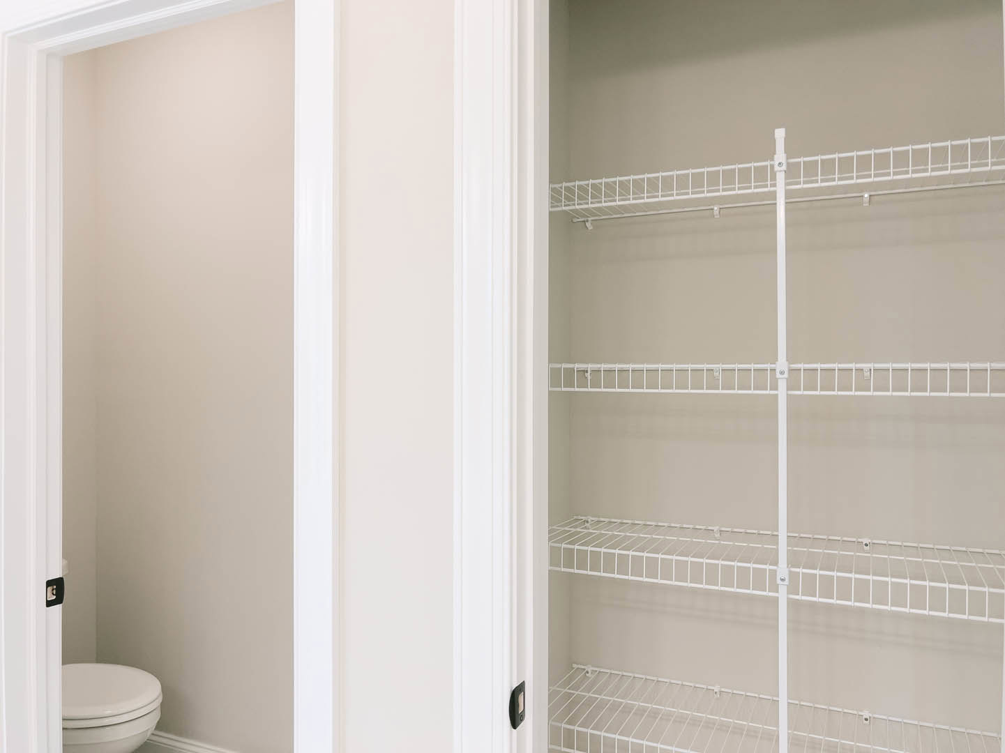 White wire shelving installed in a closet with tiled walls, adjacent to a white toilet with closed lid.