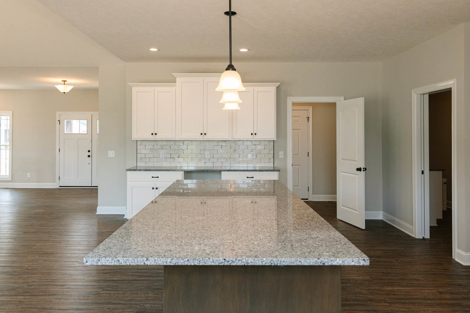 Marble kitchen island with tile flooring, granite countertops, white cabinetry, and modern ceiling light fixture