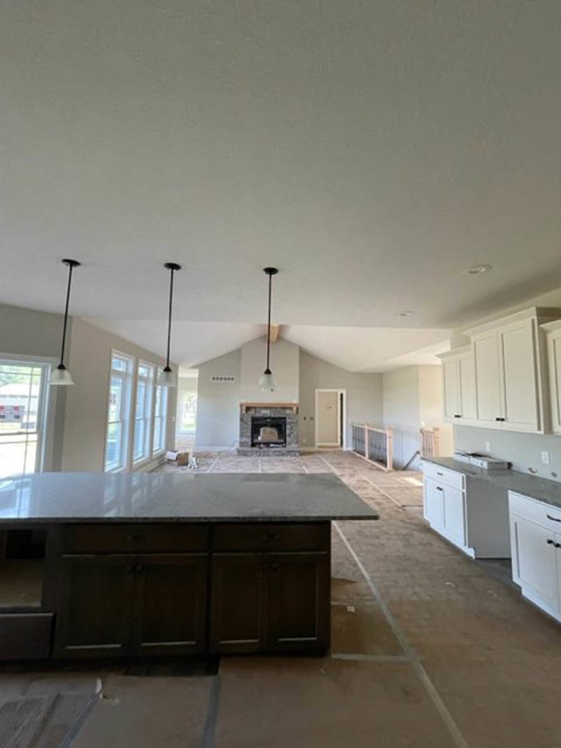 Kitchen with white cabinetry, marble island countertop, built-in fireplace, stainless steel appliances, and black hardware accents