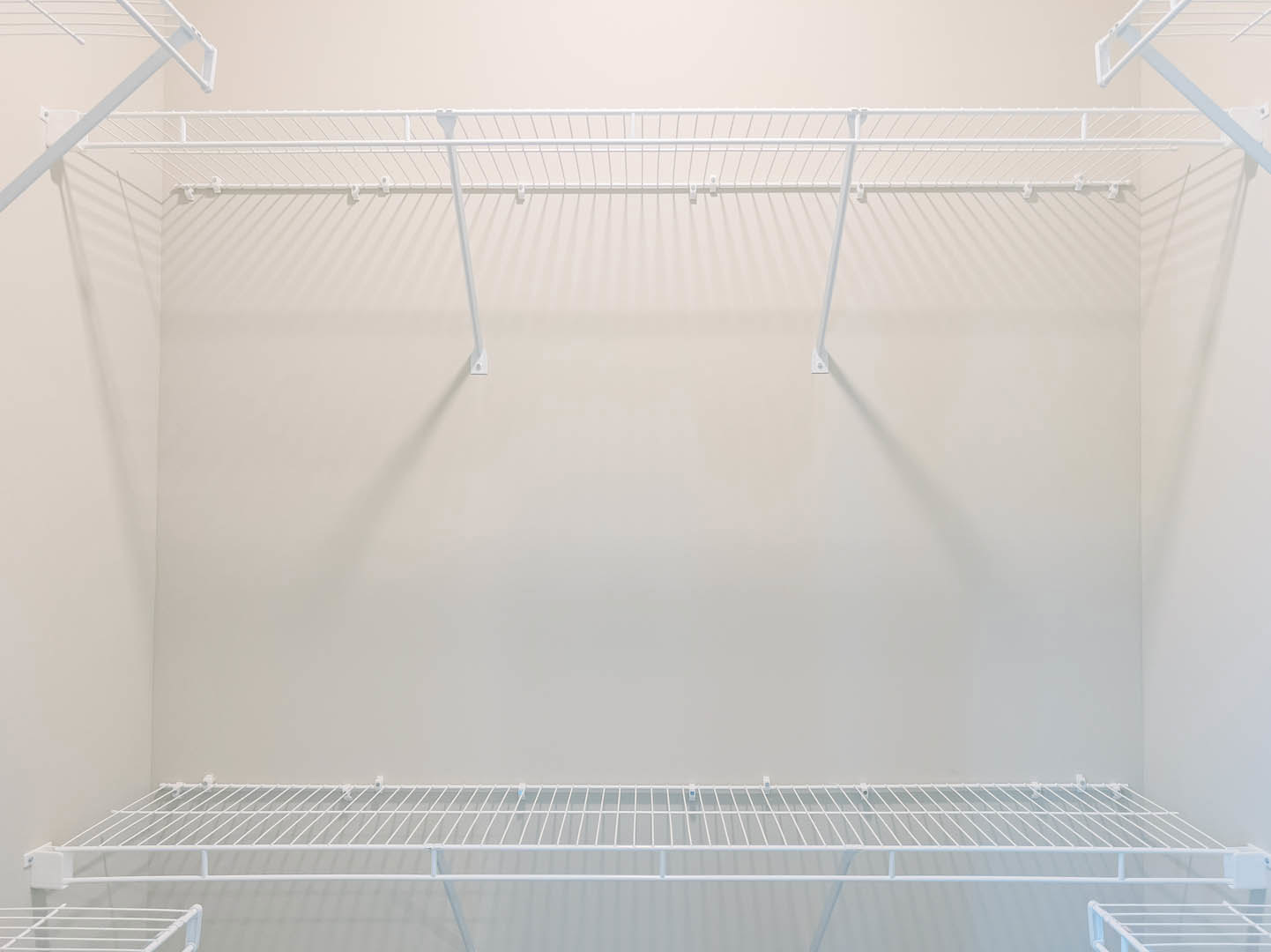 White wall-mounted shelves with metal rods and hooks, blue accent wall in background, close-up of stair railing and white metal bar.
