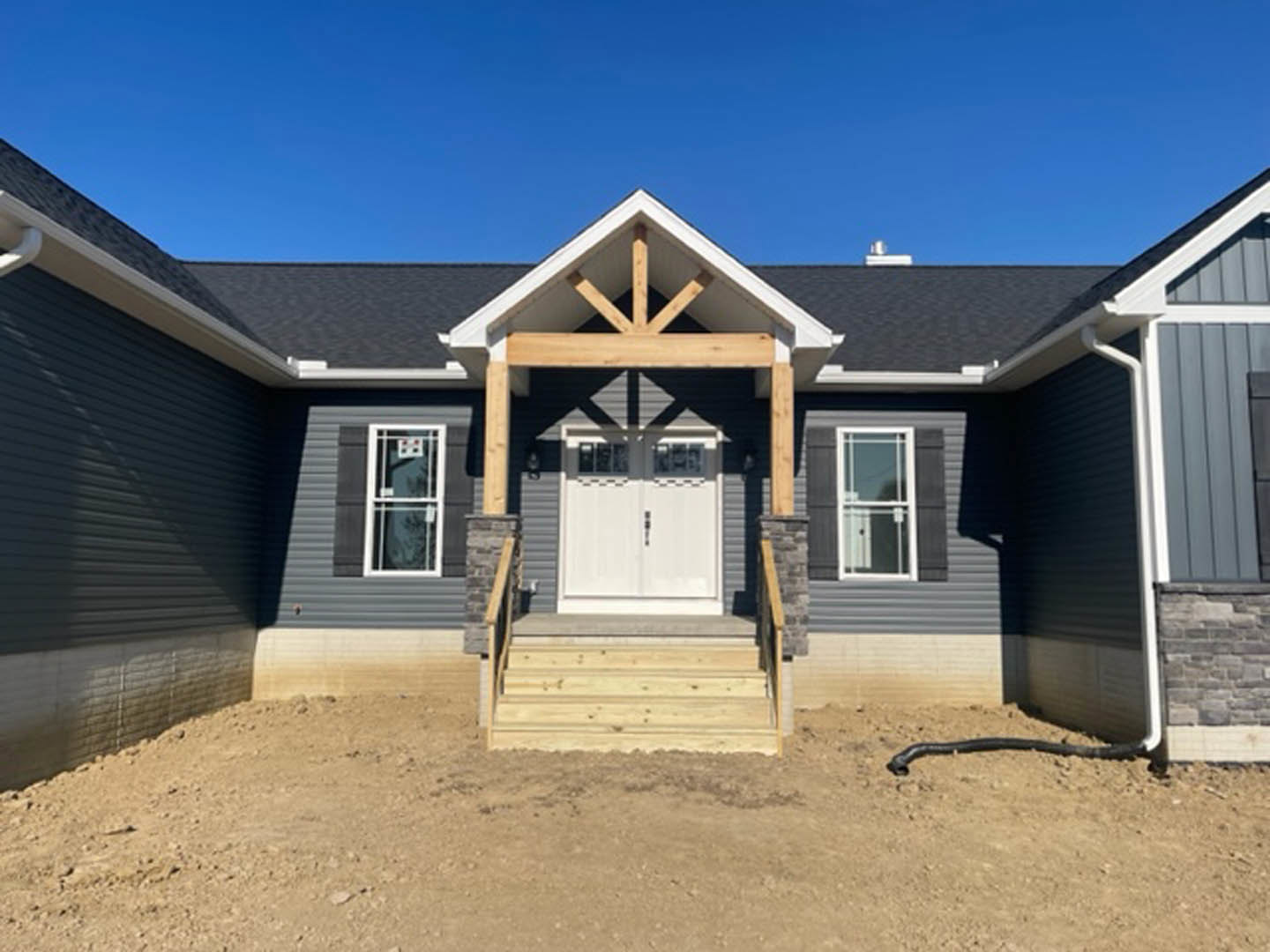 White double front doors with glass panes, wood porch and steps, white window frames, light-colored siding, outdoor entry area