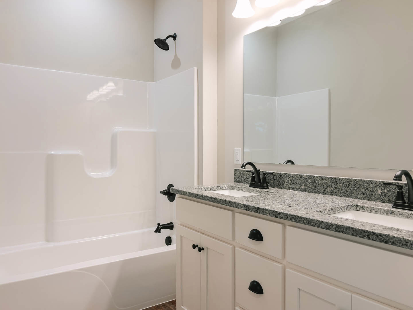 Modern bathroom with white tile walls, floating vanity with integrated sink, frameless glass shower enclosure, large wall mirror, and sleek chrome fixtures