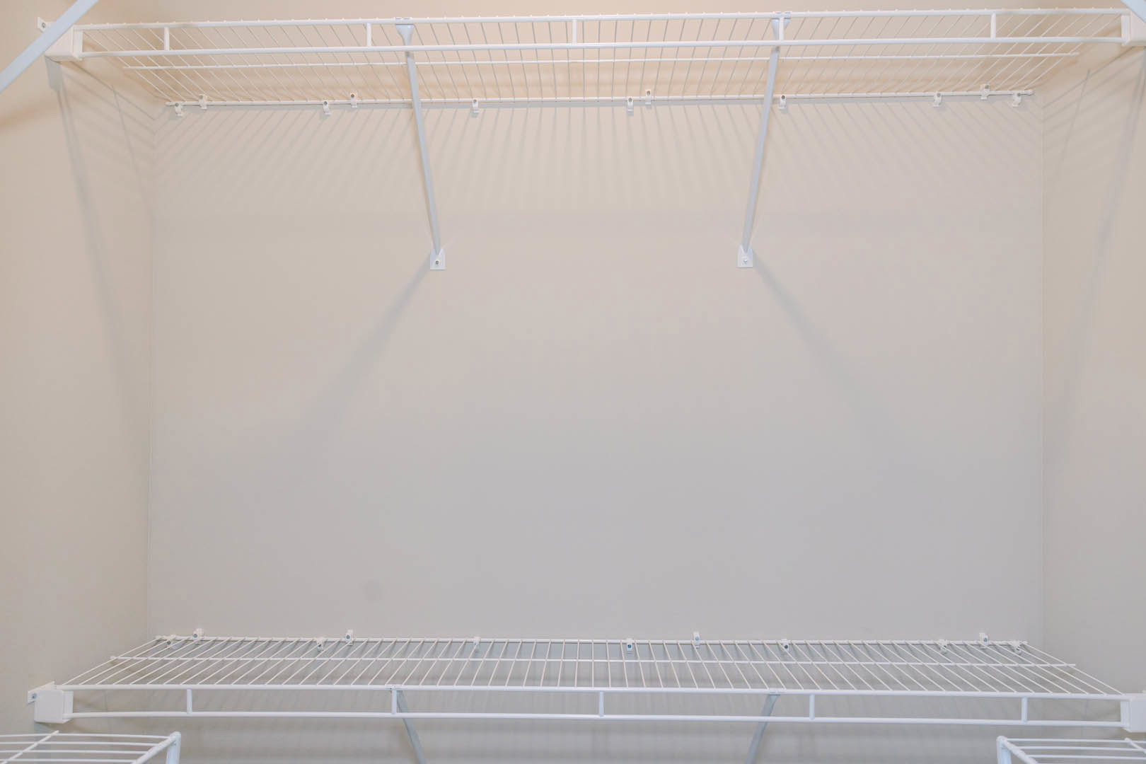 White metal shelf with horizontal bars and hooks mounted on a light-colored wall in an indoor residential space.