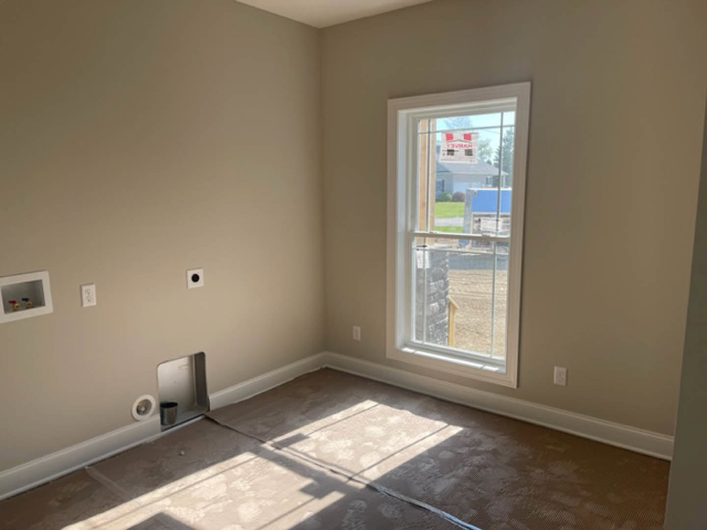 Carpeted floor in a bright room with white walls, large window, and simple ceiling.