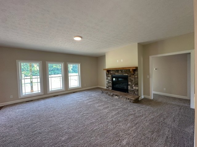Living room with carpeted floor, white plaster walls, ceiling, and central fireplace featuring a black rectangular surround with glass panel