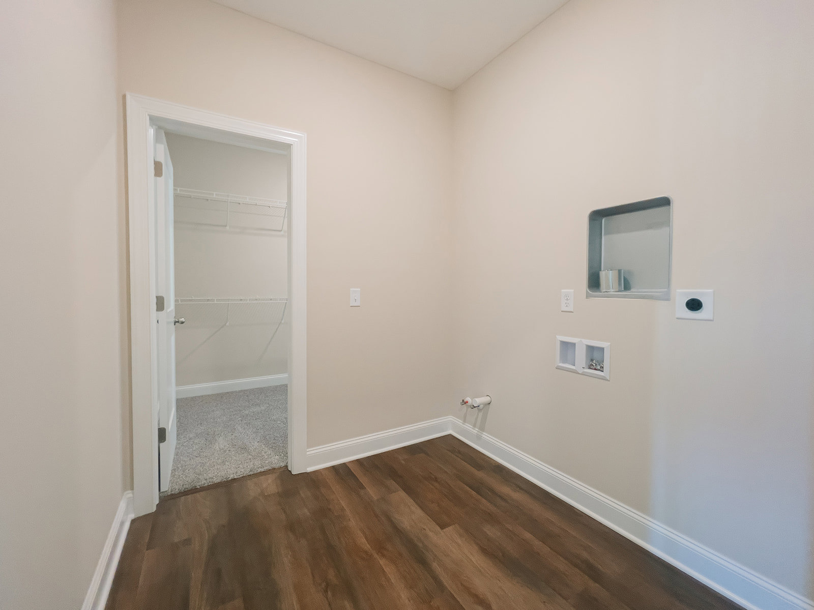 Bedroom with white closet door, metal shelf, wood laminate flooring, white baseboard trim, and glass window