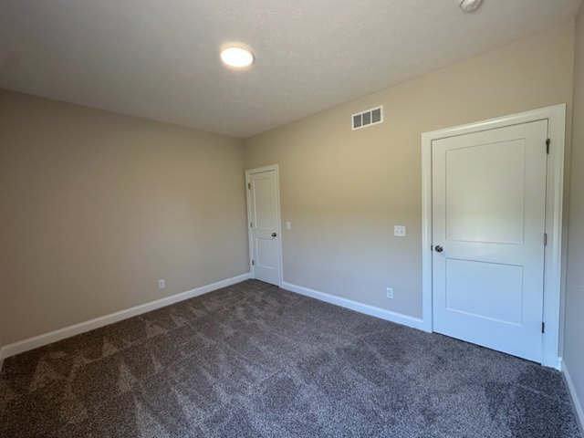 Carpeted room with white walls, paneled door, and smooth plaster ceiling