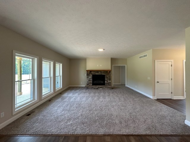 Living room featuring a white plaster fireplace, large windows with natural light, wood laminate flooring, and neutral walls with recessed ceiling lighting