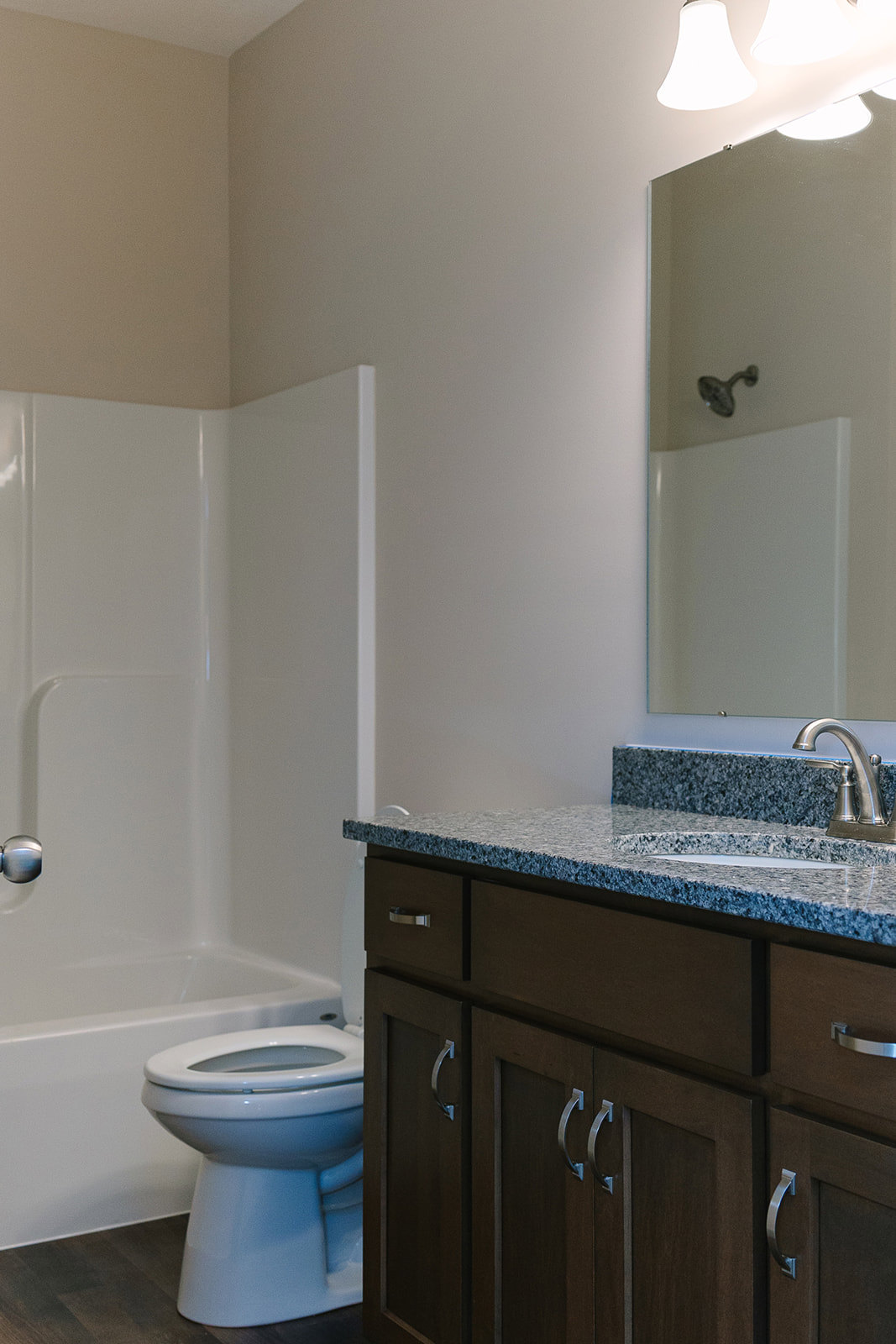 Bathroom with marble countertop, undermount sink, chrome faucet, white toilet, tiled walls, and modern light fixture