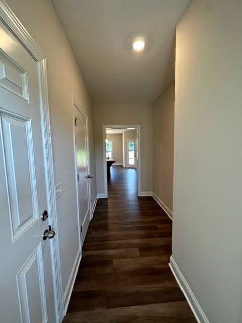 Hallway featuring dark wood floors, white paneled doors, white walls, and recessed lighting