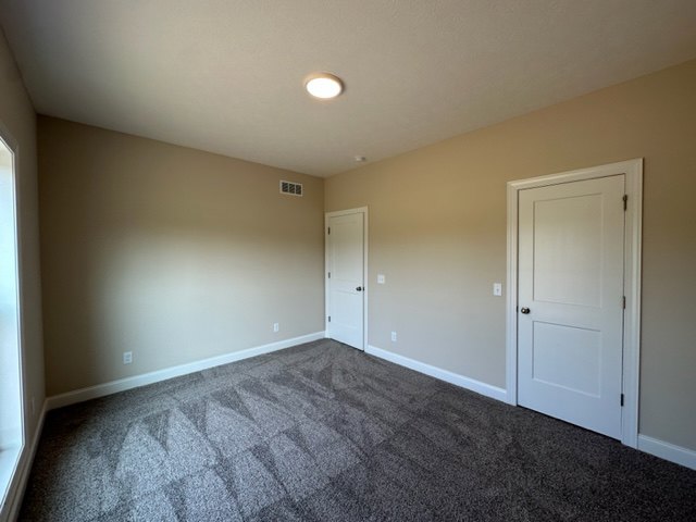 Carpeted room with two white paneled doors, light-colored walls, ceiling molding, and plaster finish