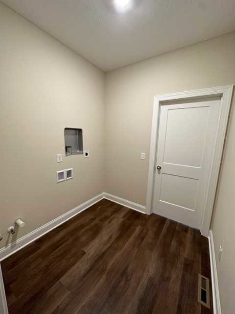 White paneled door with silver handle, dark wood laminate flooring, smooth plaster walls, recessed ceiling light in a modern interior room