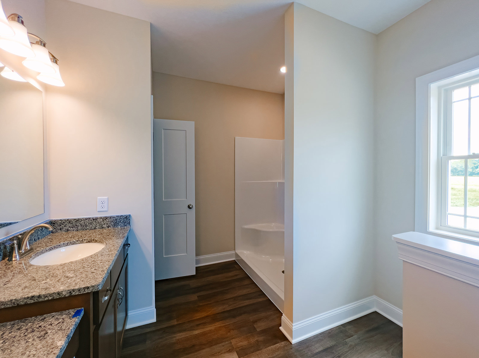 White-tiled bathroom featuring a glass-enclosed shower, modern rectangular sink with chrome faucet, light wood cabinetry, and a frosted window for natural light