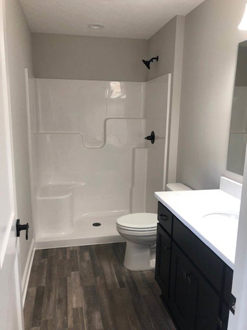 Modern bathroom with white toilet, rectangular sink set in white countertop, light gray tile floor, and neutral wall tiles