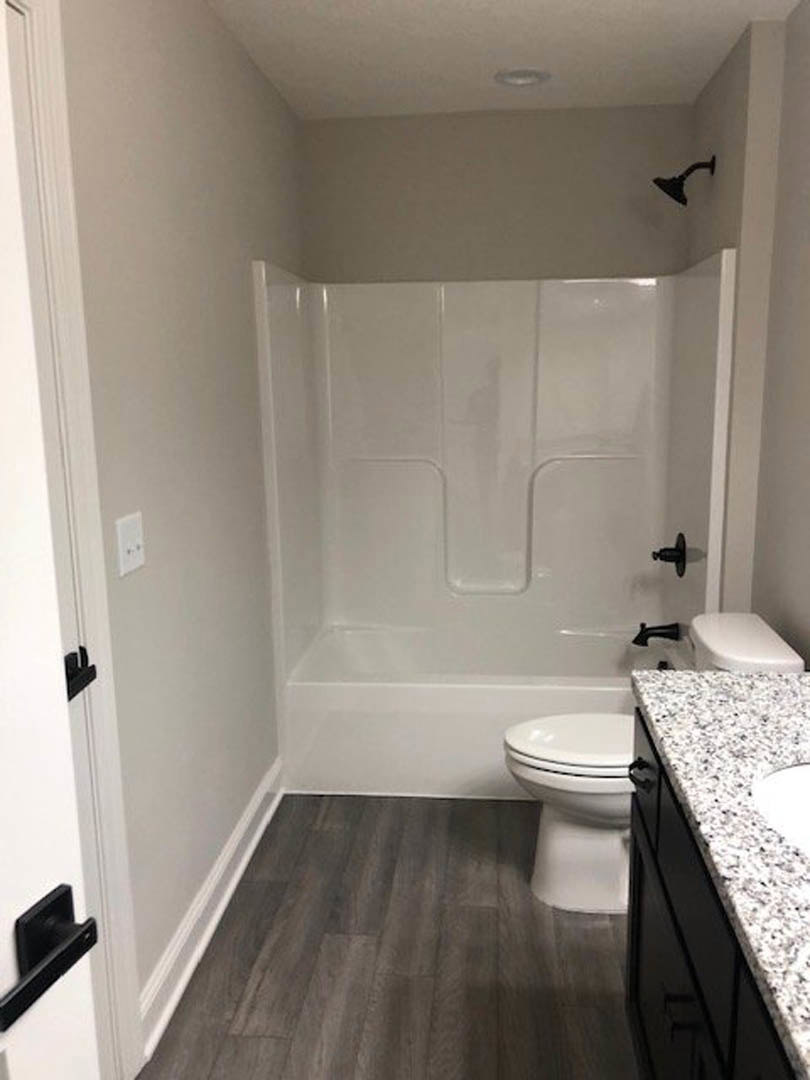 Modern bathroom featuring white ceramic toilet and rectangular sink set in a stone countertop, light gray tile flooring, and neutral wall tiles.