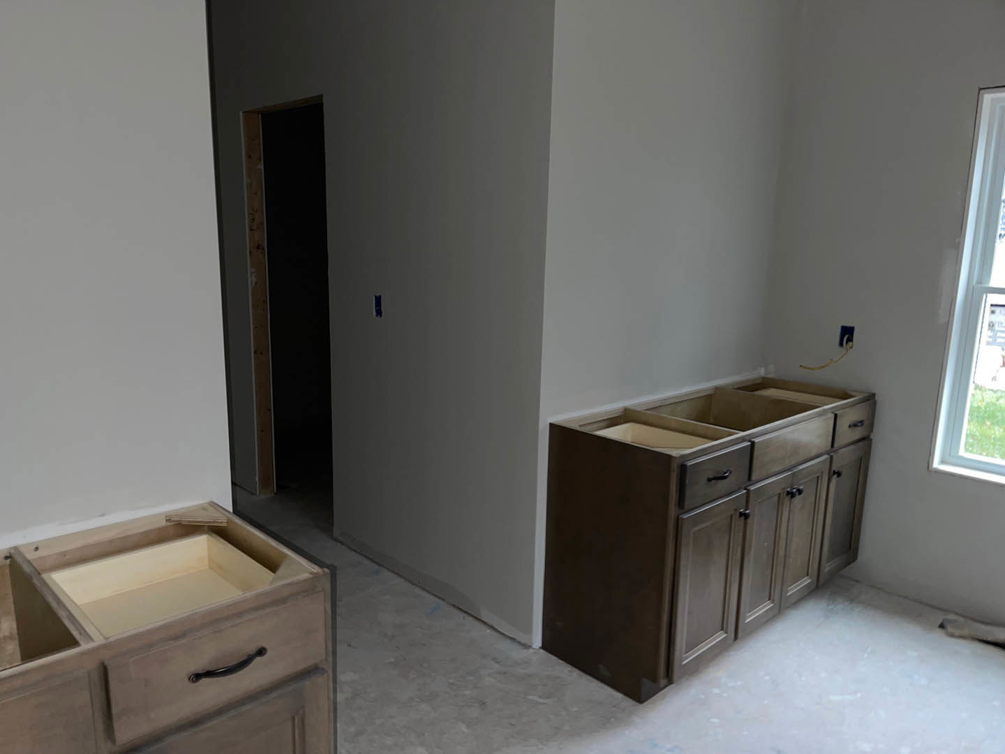 Modern kitchen featuring light wood cabinets and drawers, stone countertop, stainless steel appliances, and large window with natural light.