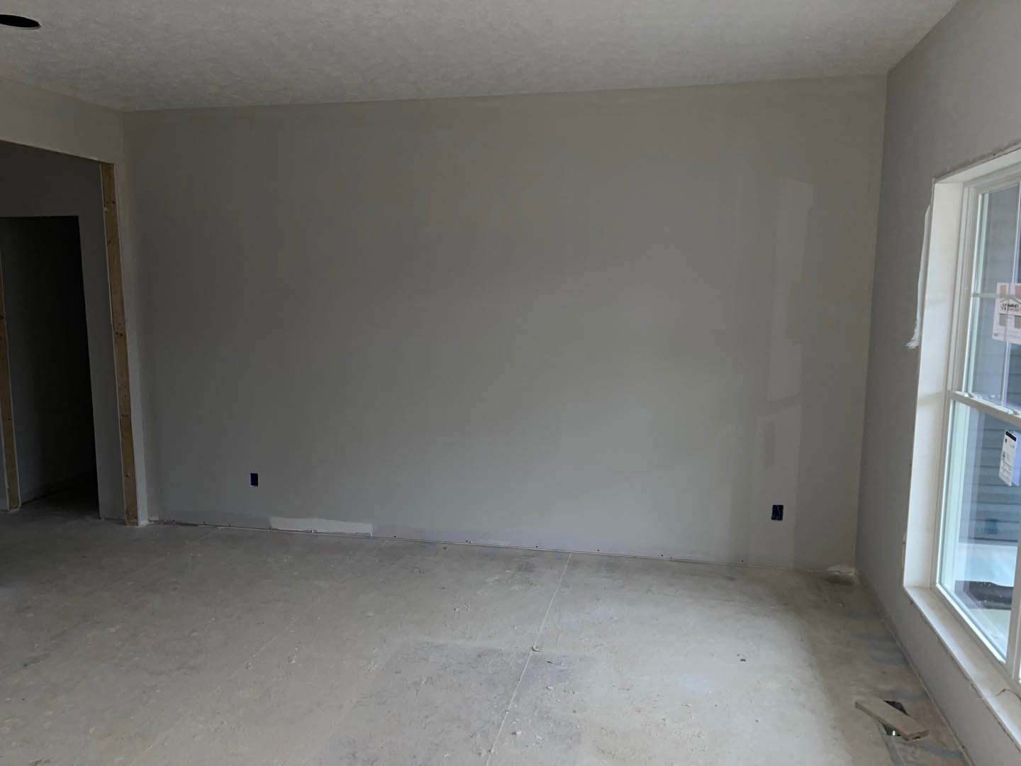White-walled room with smooth white flooring and a large window letting in natural light
