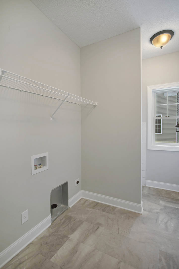 White-painted room featuring a built-in white shelf, tile flooring, window with white blinds, two faucets mounted on a white framed box, close-up of a modern light fixture, and