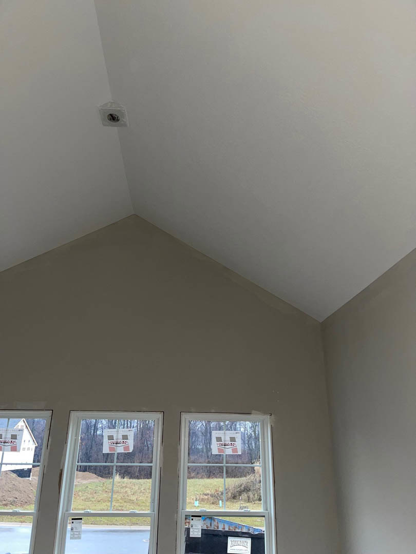 White plaster ceiling with recessed lighting, large windows allowing daylight, and smooth interior walls in a modern residential space
