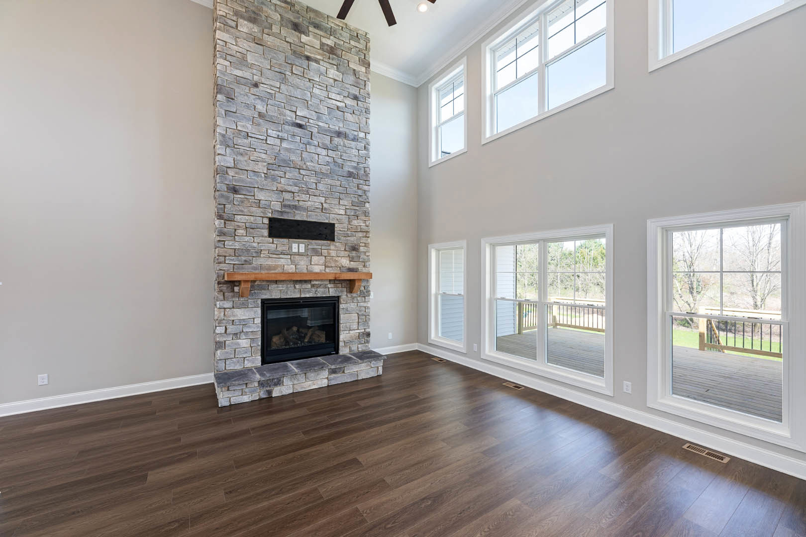 Hardwood floor and stone fireplace with glass door, wood burning inside, black accent stripe on brick wall, window in den.