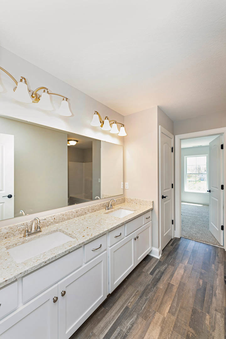Bathroom featuring a marble countertop, large mirror above the sink, white walls with a black accent stripe, modern light fixture, and white cabinetry.