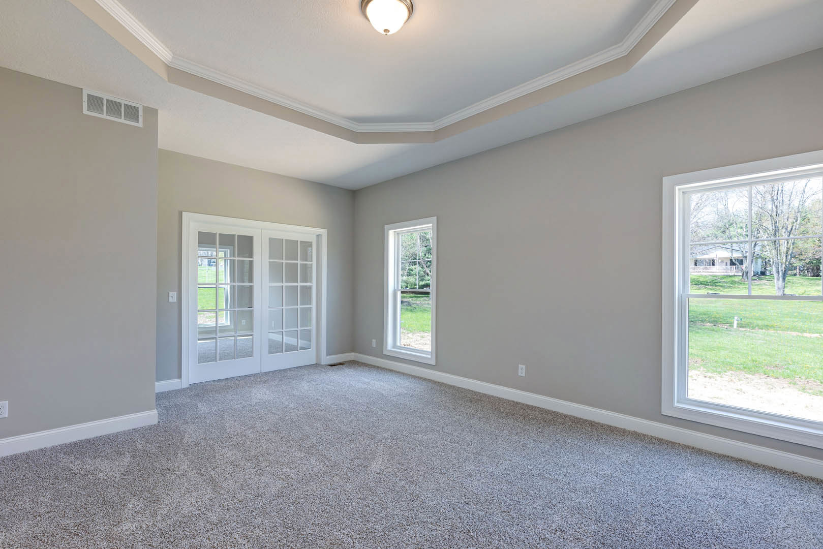Carpeted room with white walls, double glass-paneled doors, large window overlooking lawn and neighboring house, ceiling light fixture, crown molding, and plaster ceiling.