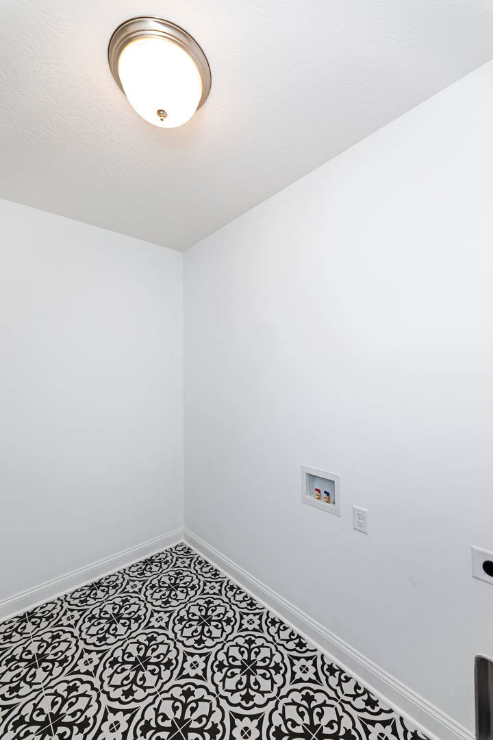 Black and white tile floor in a room with plaster walls and a brass ceiling light fixture