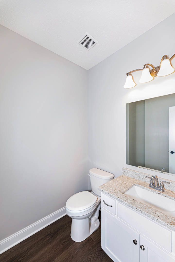 Modern bathroom with white ceramic sink, chrome faucet, wall-mounted mirror, and toilet on light gray tile floor
