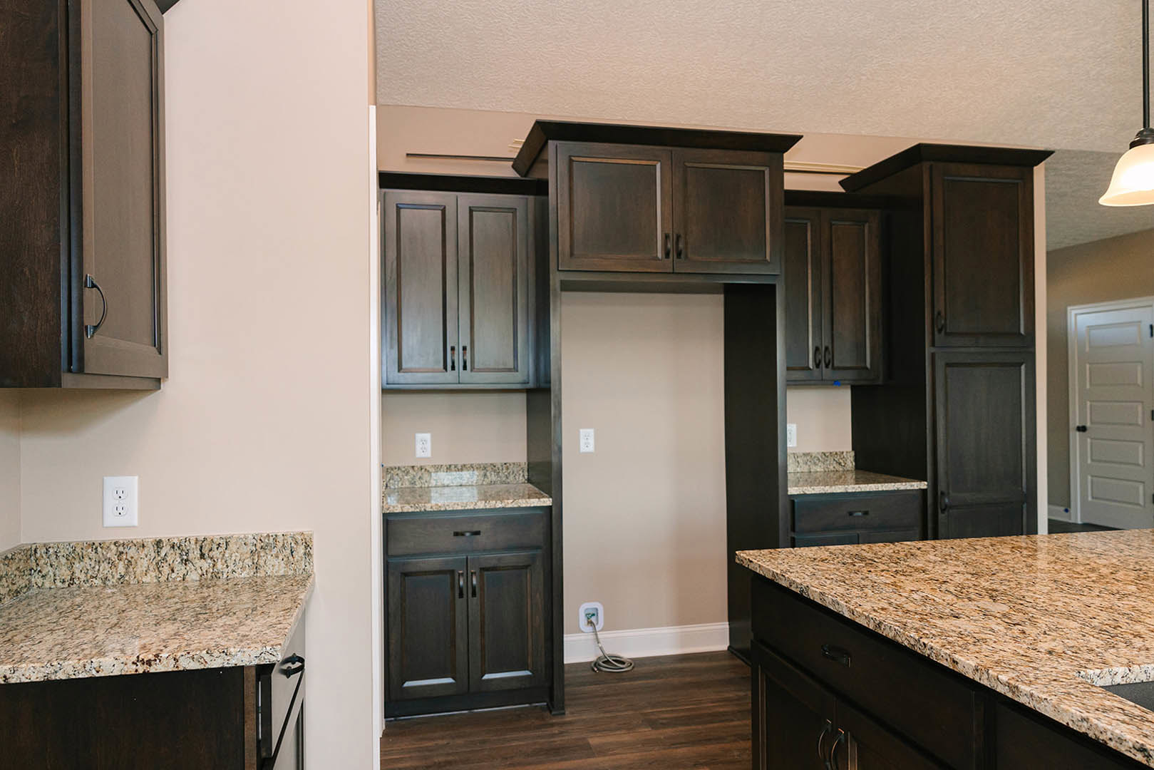 Kitchen with dark wood cabinetry, granite countertops, stainless steel sink, and tile backsplash