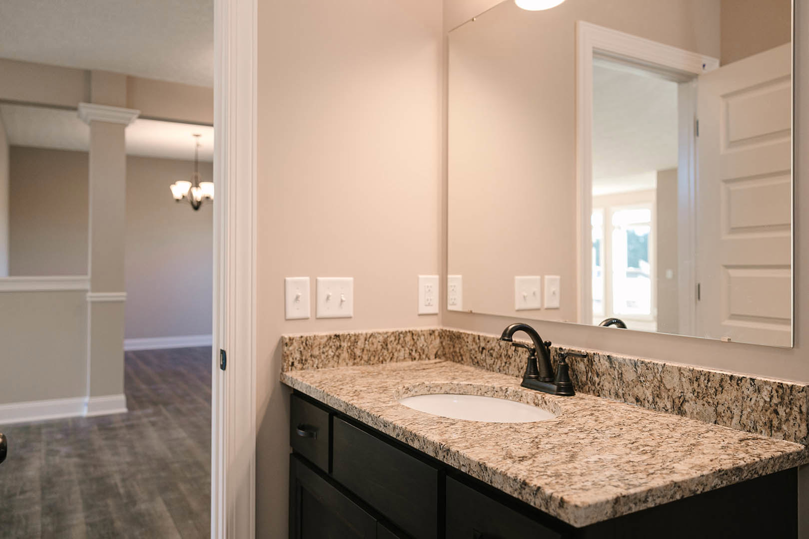 Marble bathroom countertop with undermount sink, chrome faucet, large framed mirror, white cabinetry, and tile backsplash