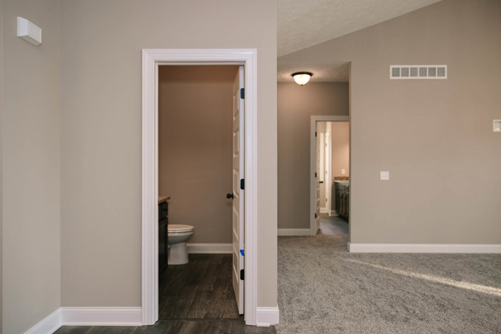 Modern bathroom with two white toilets centered on gray tile flooring, white plaster walls, ceiling light fixture, and a window providing natural light