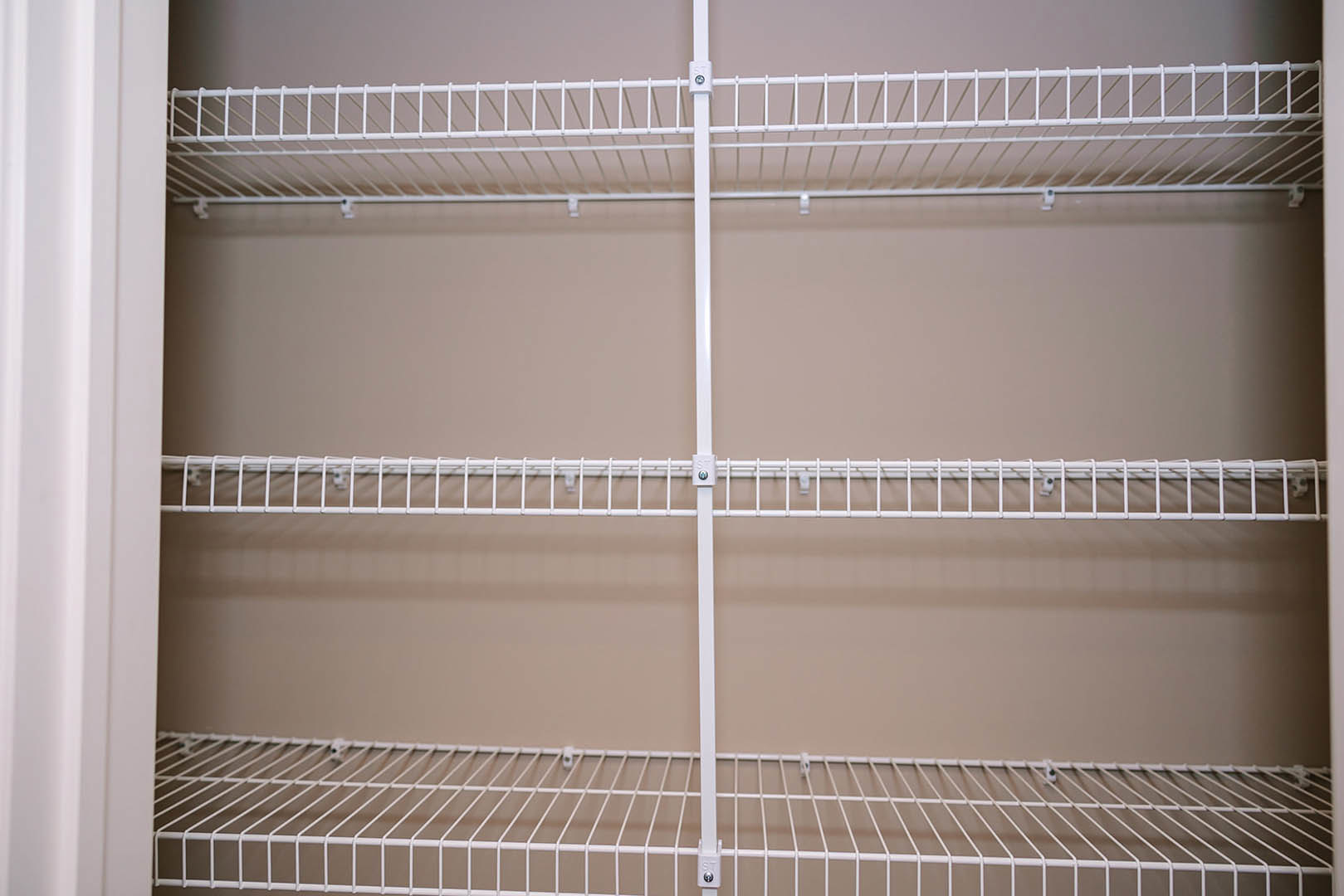 White wire shelving mounted on a white wall in a residential interior, featuring metal racks and support poles.