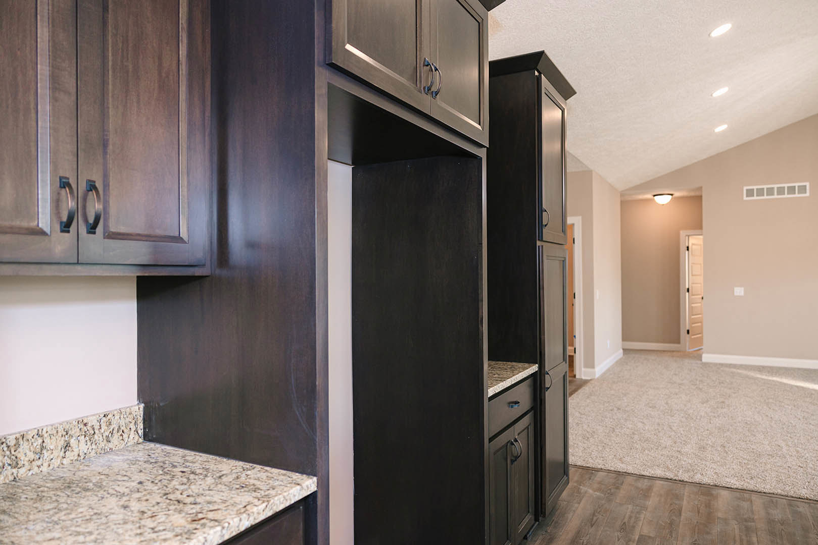 Kitchen with dark wood cabinets, granite countertops, stainless steel appliances, and hardwood flooring