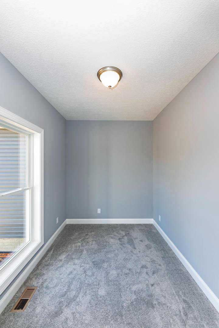 Carpeted room with white walls, ceiling-mounted light fixture, floor vent, and window with closed blinds