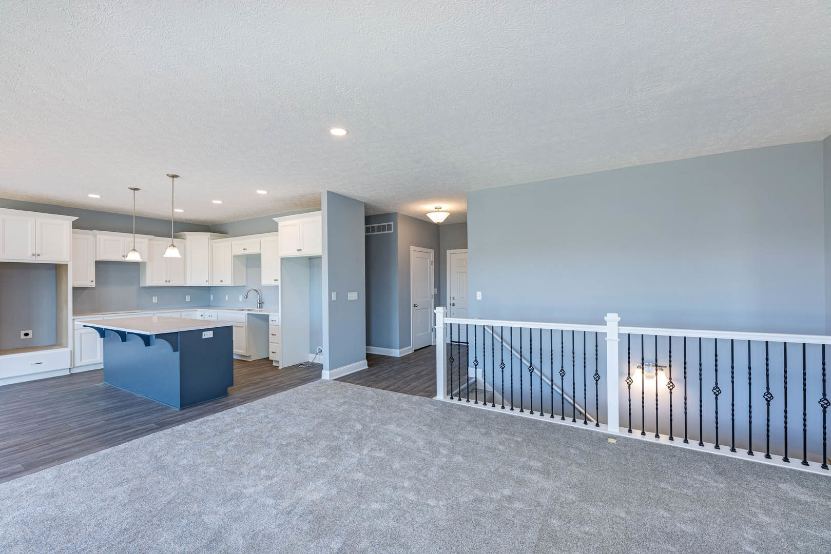 Open-concept room featuring an indoor pool, blue and white kitchen island, carpeted floor, staircase, and white ceiling with recessed lighting