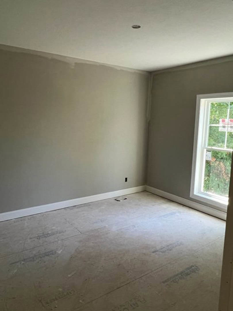 Bright room with white plaster walls, large window, light flooring, and minimal decor