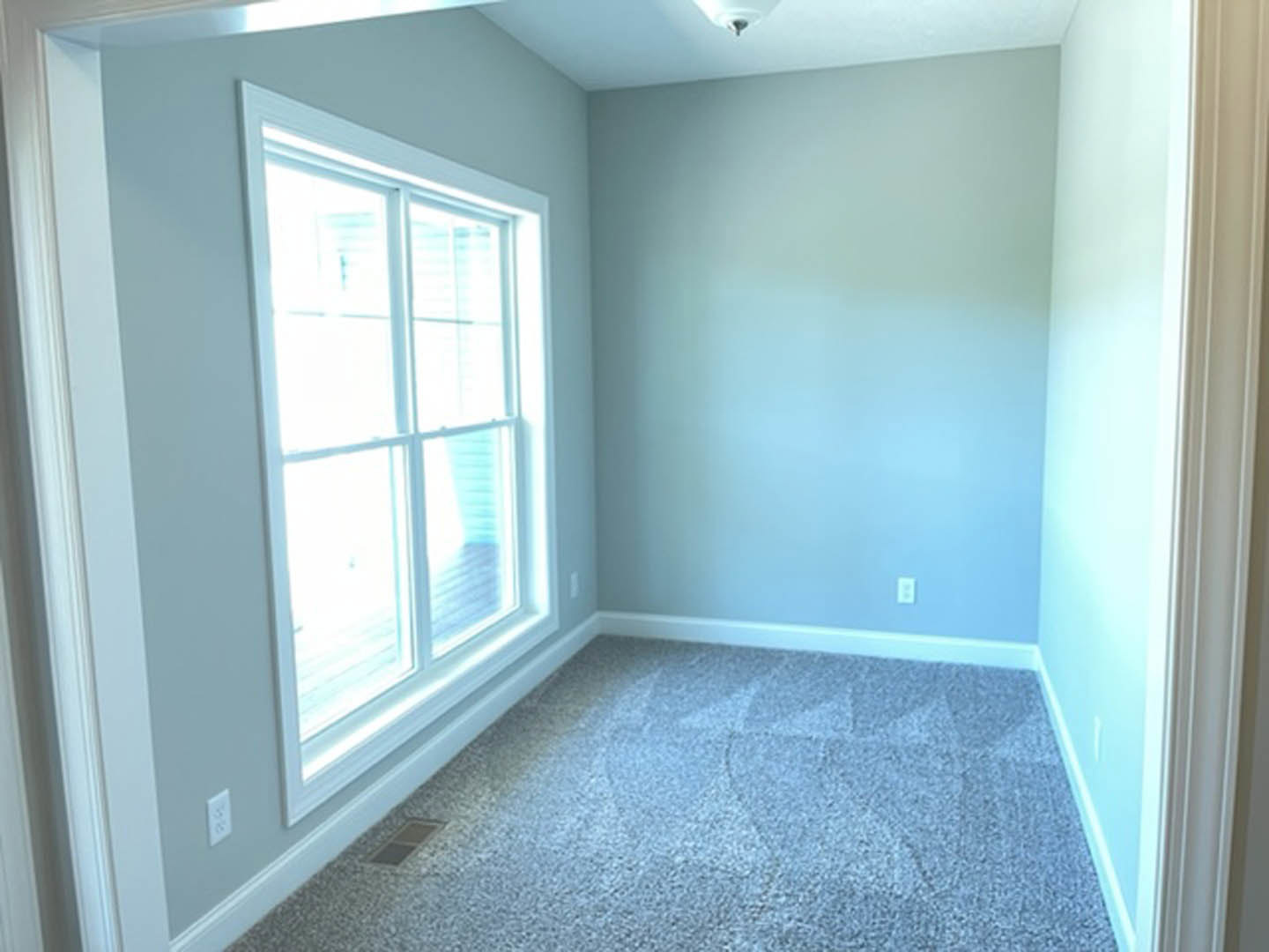 Carpeted bedroom with white-framed window, blue accent wall, and ceiling light fixture