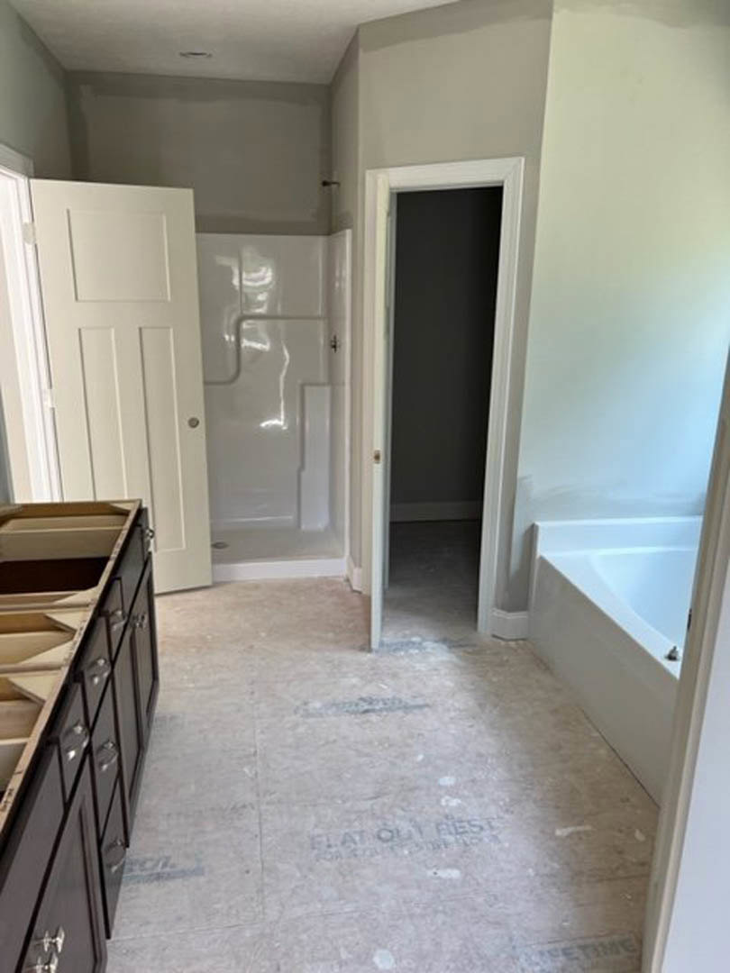 Modern bathroom featuring a freestanding bathtub, white vanity with integrated sink, tile flooring, and white paneled door with chrome handle