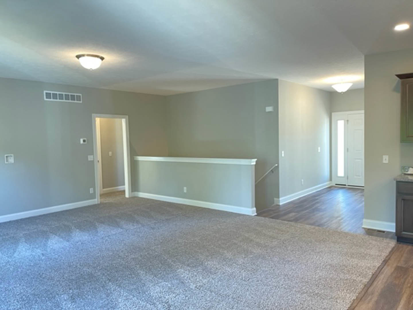 Carpeted room with white walls, white door partially open letting in light, ceiling with recessed lighting