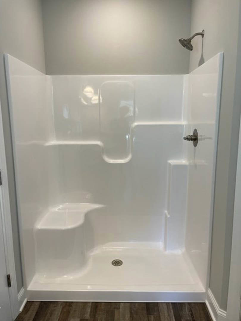 White tile shower with chrome shower head and recessed ceiling light