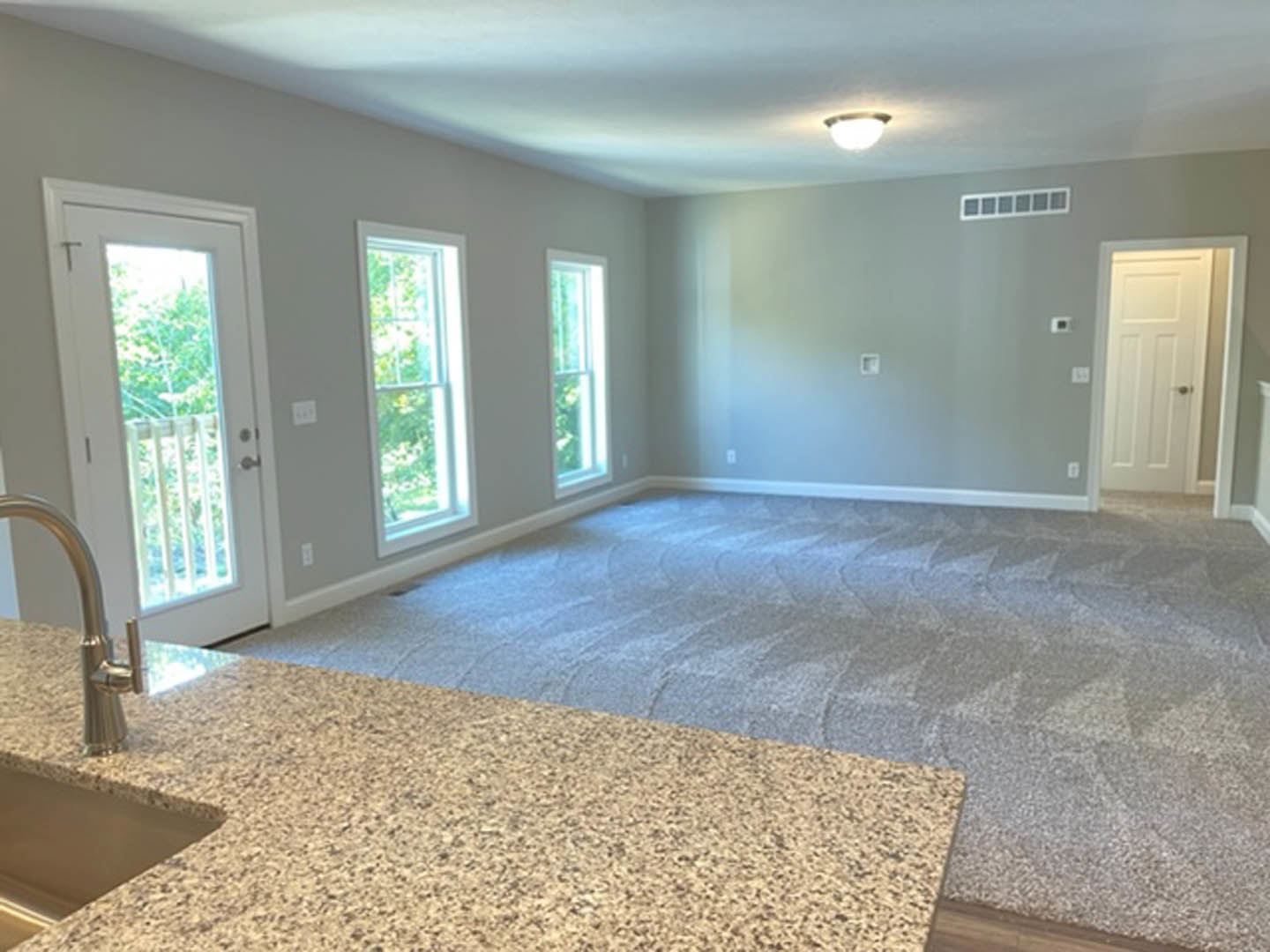 Marble countertop with chrome faucet, carpeted floor, white door with glass window, neutral walls, recessed ceiling lighting