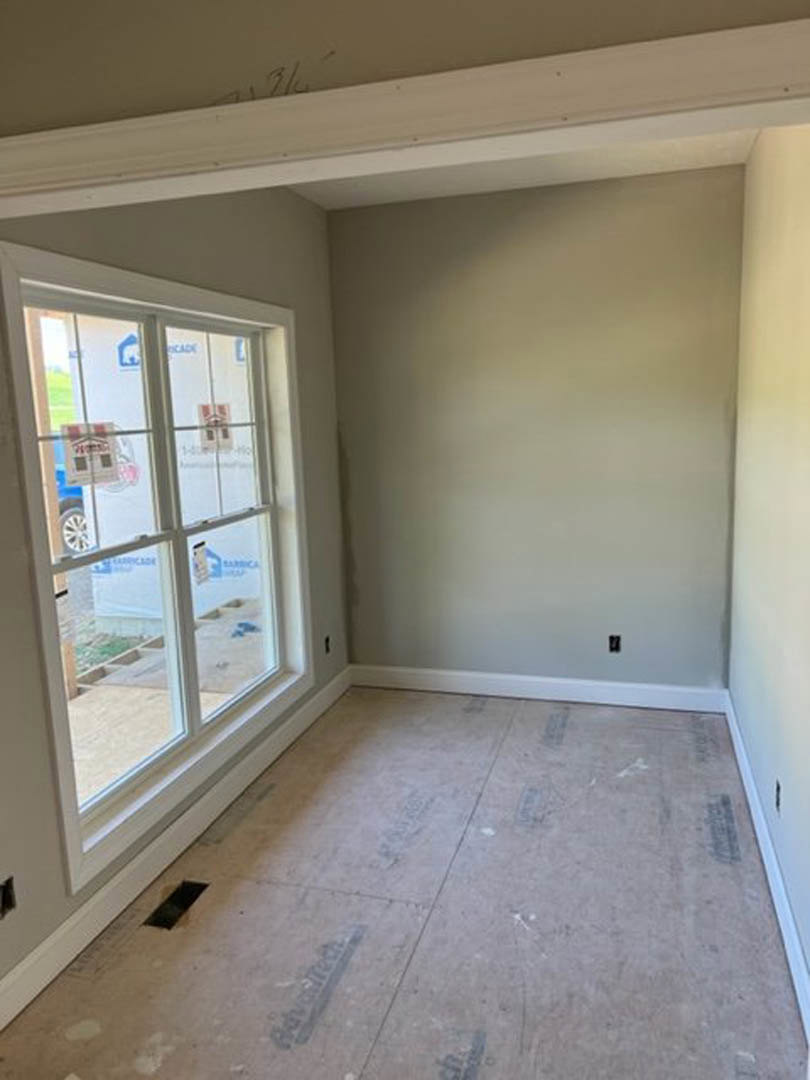 Sunlit room with large window, white plaster walls, and light-colored tile flooring