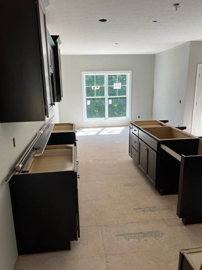 Kitchen featuring matte black cabinets and drawers, light wood flooring, a window with stickers, and a black rectangular appliance with white trim.