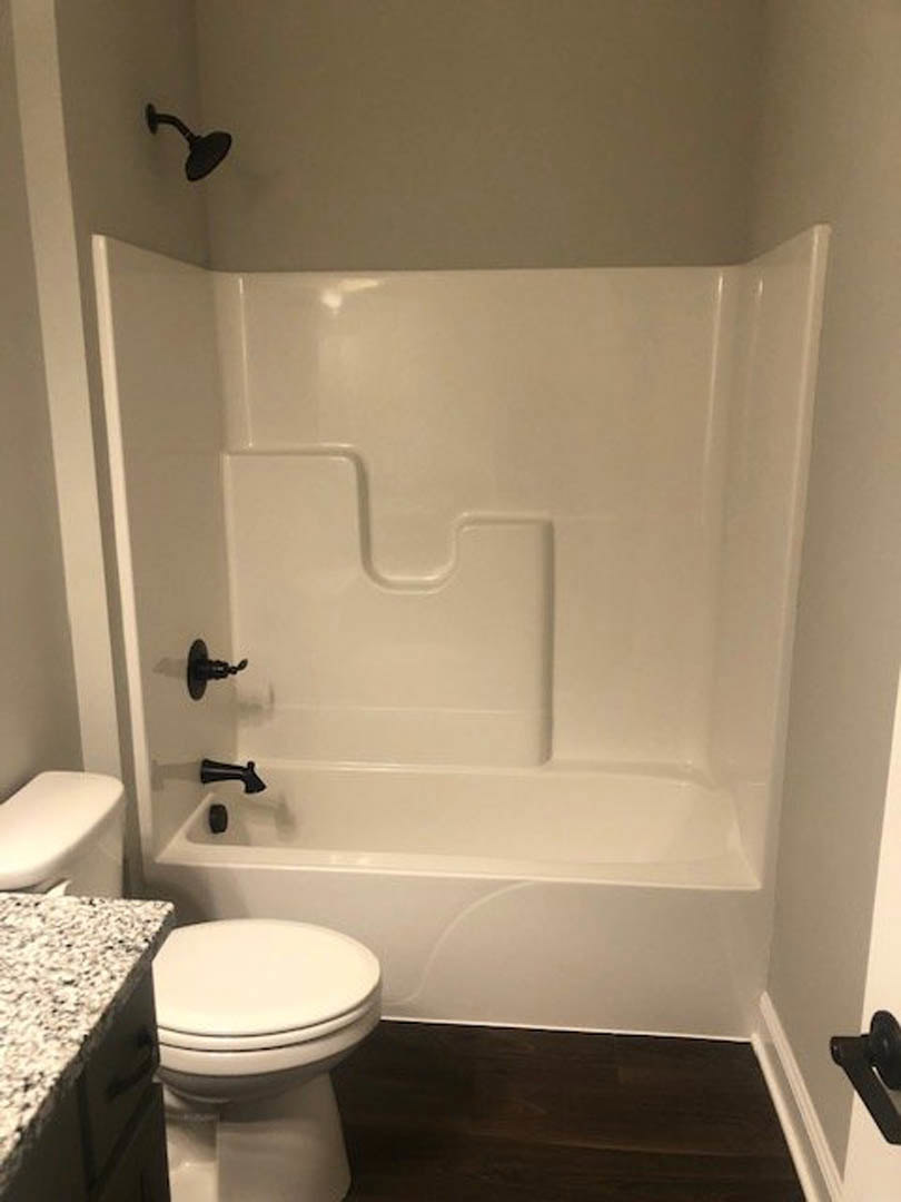 Modern bathroom with white toilet, glass-enclosed shower, light tile walls, and sleek countertop