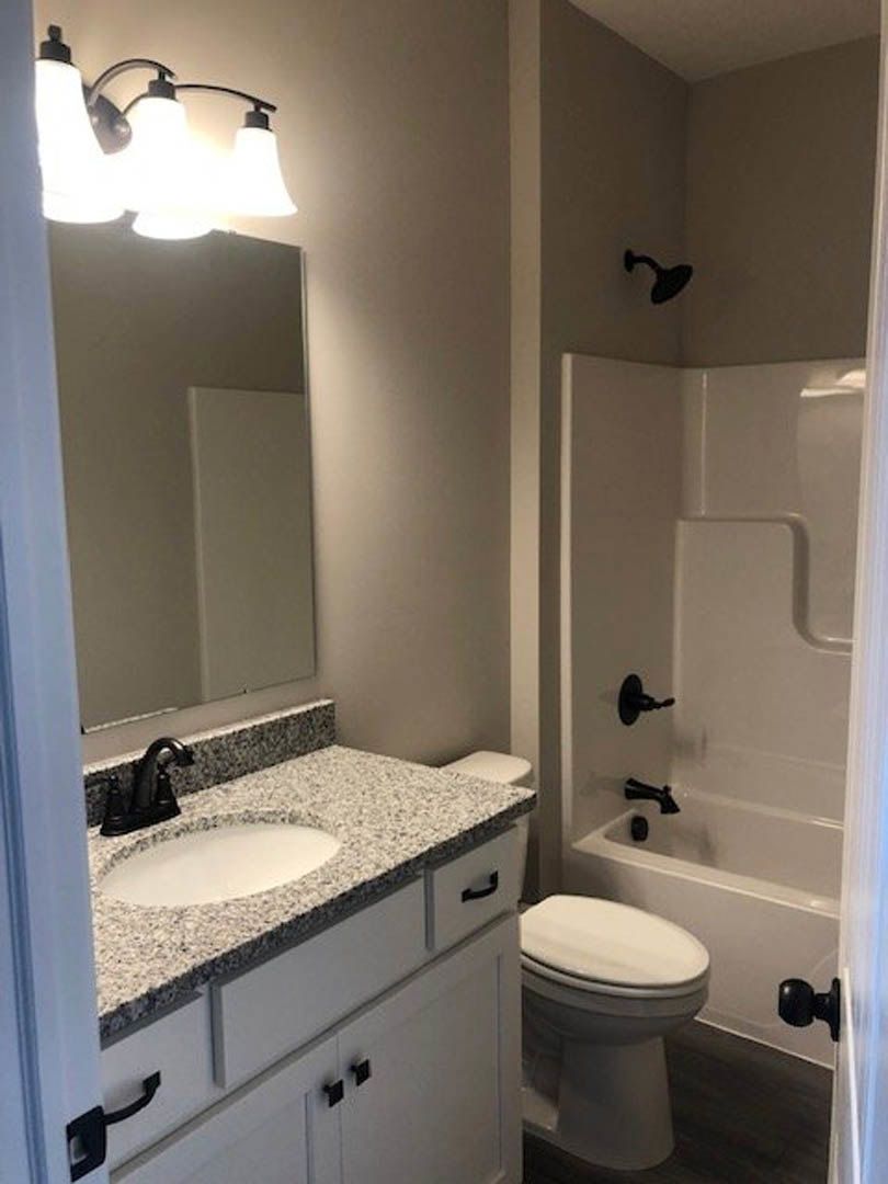 Modern bathroom featuring a white ceramic sink with chrome faucet, glass-enclosed shower with tiled walls, large wall mirror, and neutral tile flooring