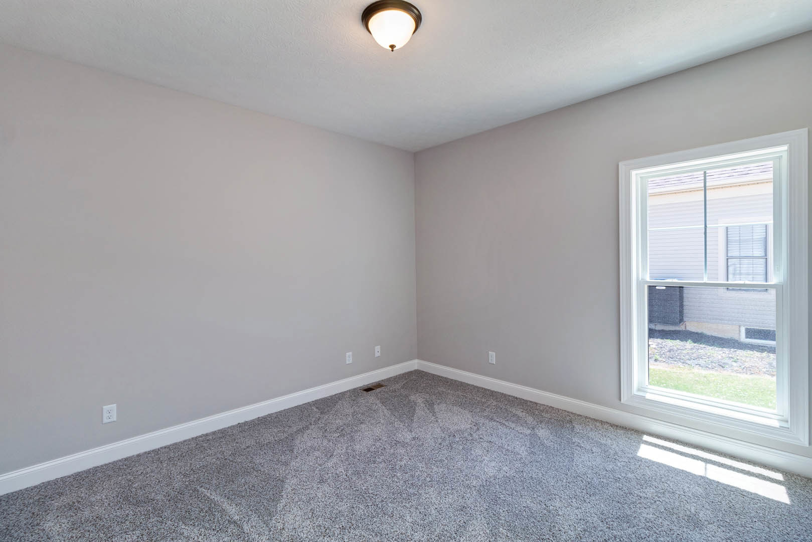 Carpeted bedroom with white-framed window, plaster walls, ceiling light fixture, and crown molding