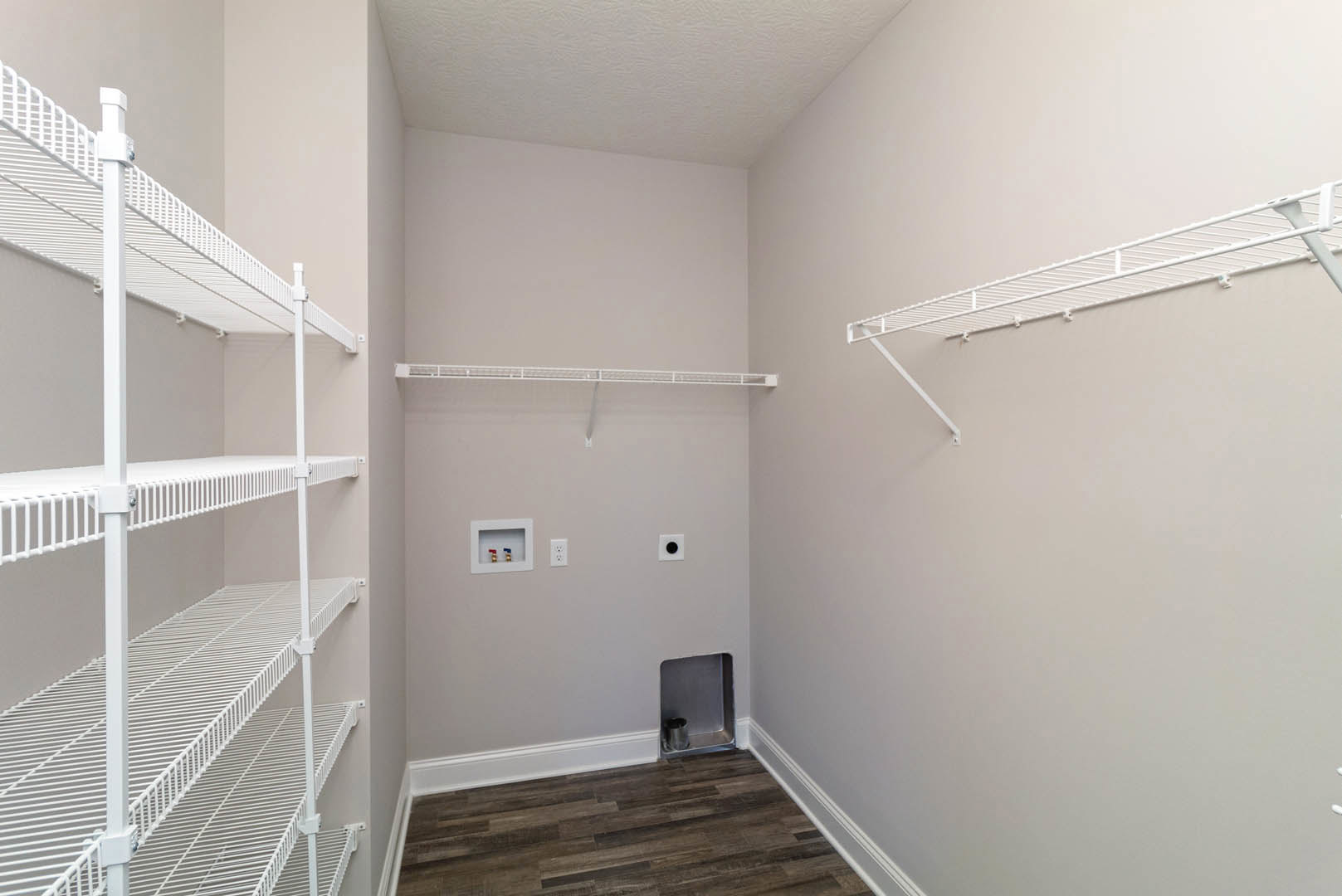 White built-in shelves with metal containers and decorative items, wood flooring with white baseboards, plaster walls, and a white ceiling.