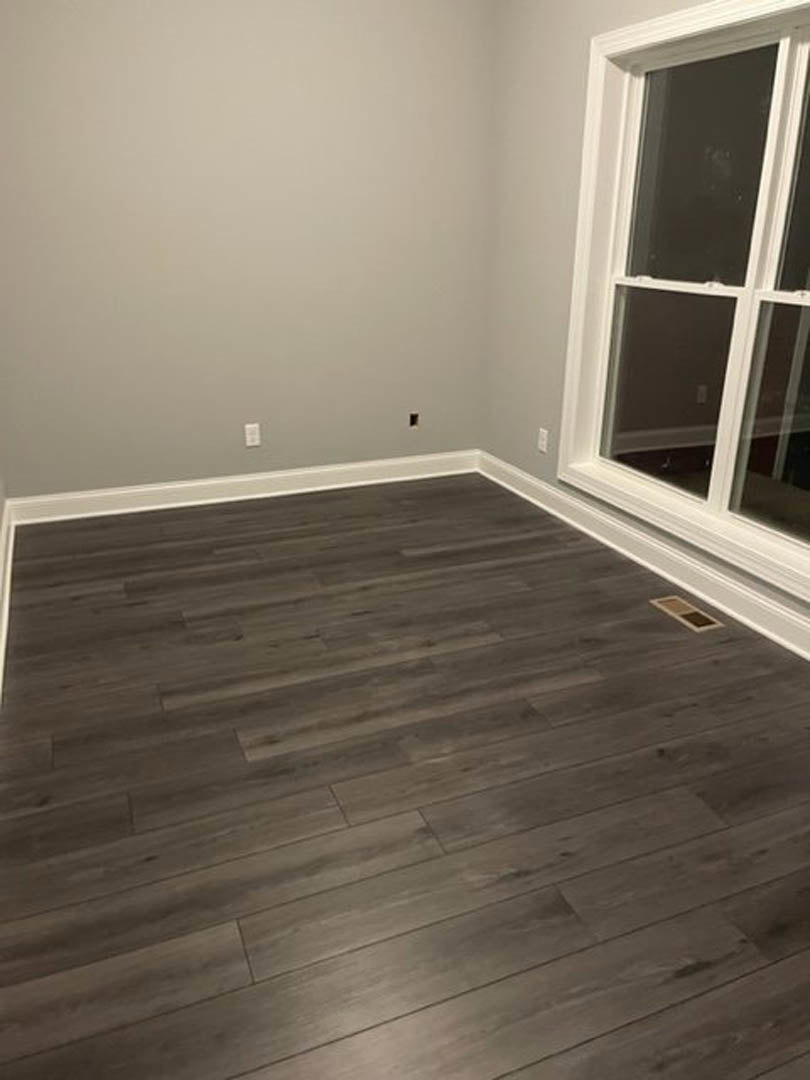 Wood flooring in a room with a white-framed window and built-in white shelf